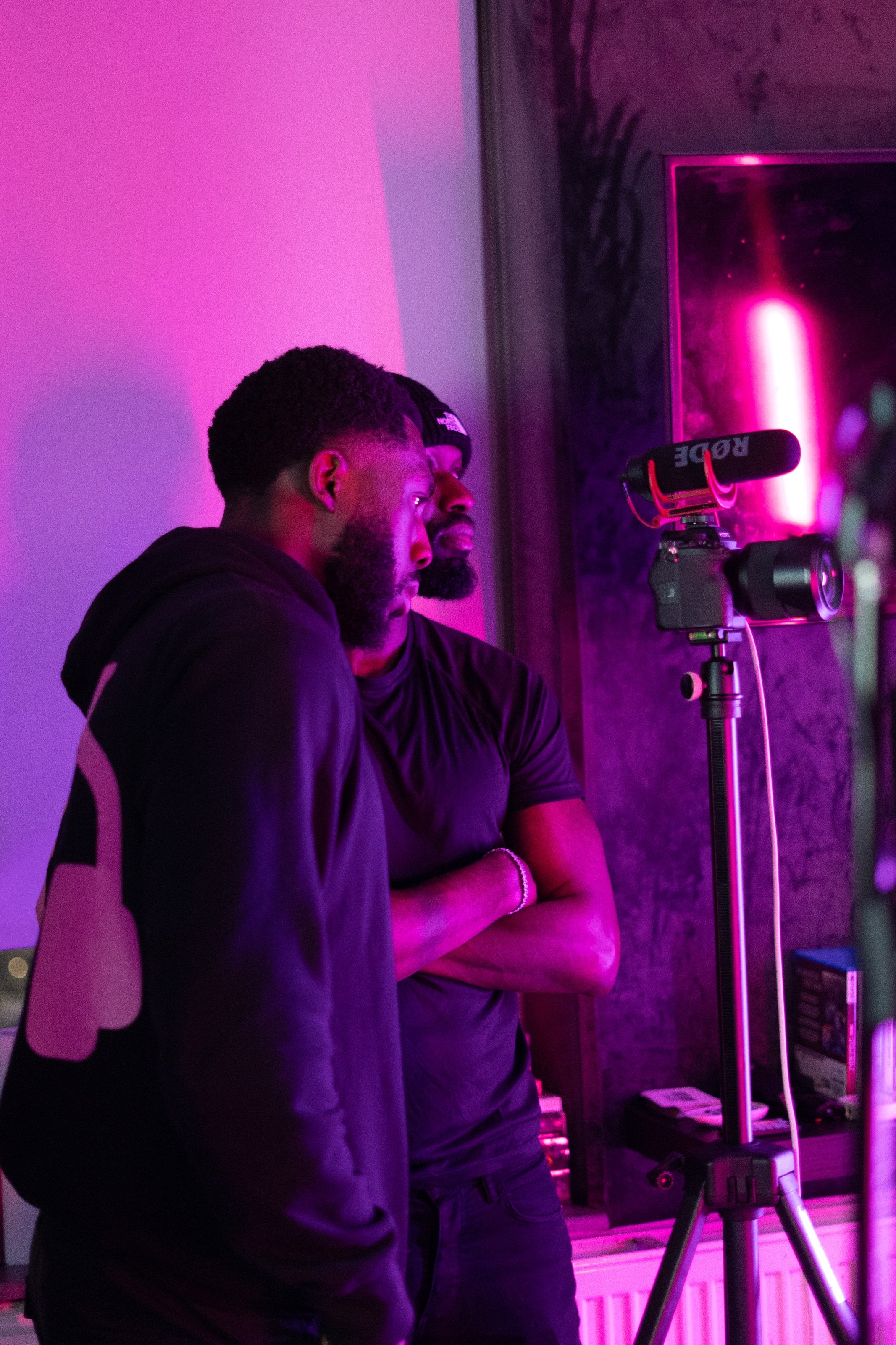 A videographer framing a shot in magenta light